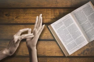 sign language for jesus next to bible on a table